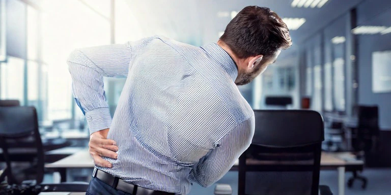 Eine Person in einem Büro mit Rückenschmerzen