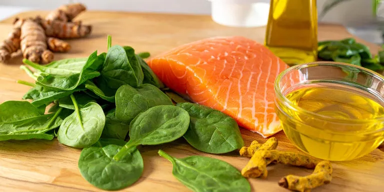 Frischer Lachs, Olivenöl, Spinat und Kurkuma in einer mediterranen Küche als entzündungshemmende Zutaten.