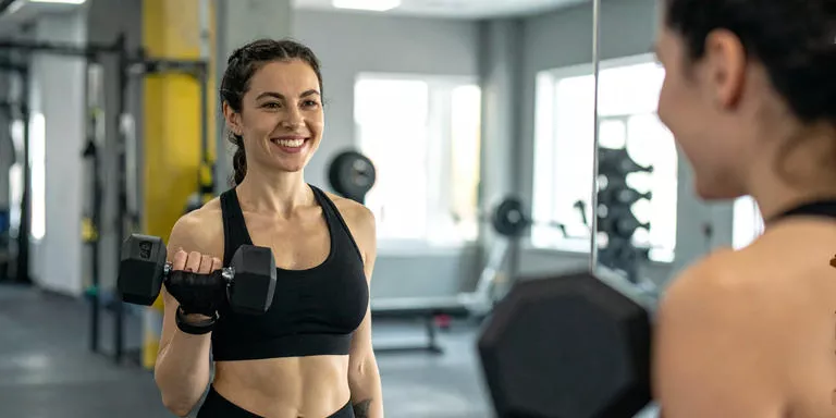Frau beim Krafttraining mit Hanteln, sichtbar definiert und selbstbewusst