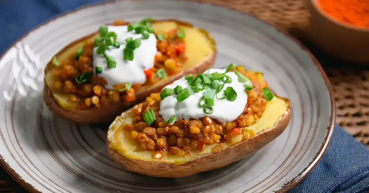 Gebackene Kartoffelhälften mit würziger Linsenfüllung, serviert mit Skyr und frischen Kräutern.