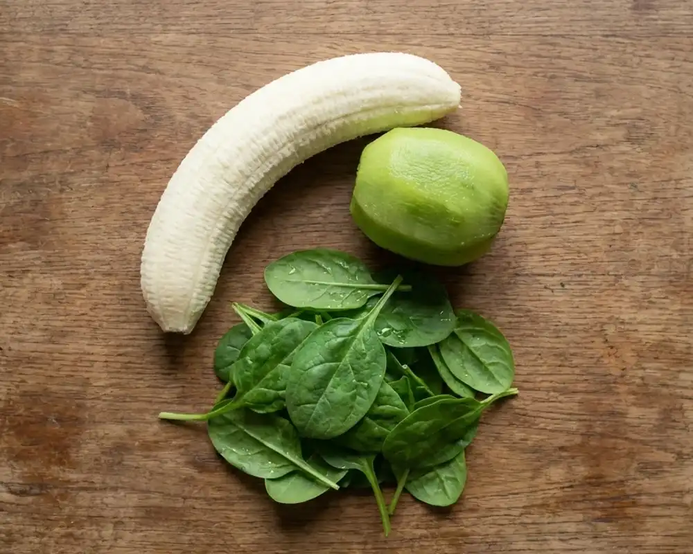 Geschälte Banane, Kiwi und frischer Babyspinat vorbereitet auf rustikalem Holztisch für Smoothie Bowl