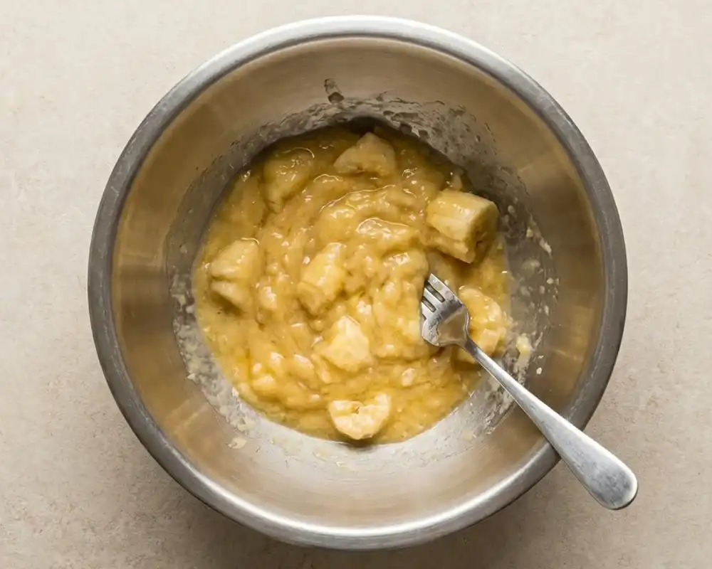 Zerdrückte Bananen in Edelstahlschüssel für Protein-Bananen-Muffins
