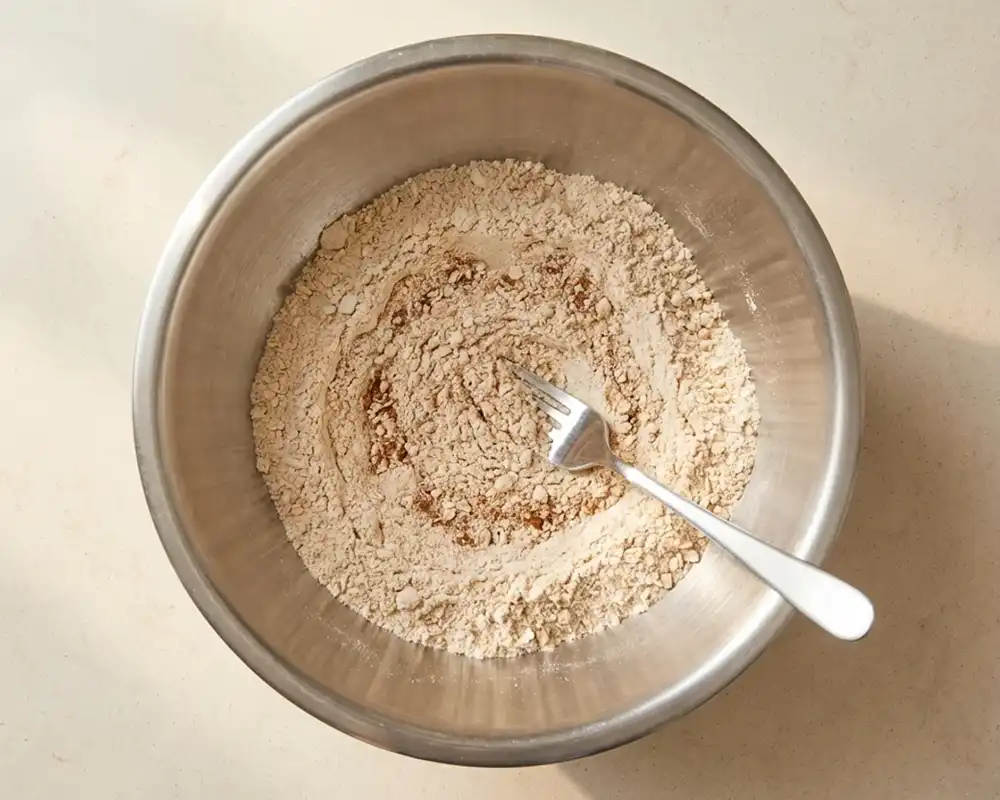 Trockene Zutaten für Protein-Bananen-Muffins in Edelstahlschüssel vermischt