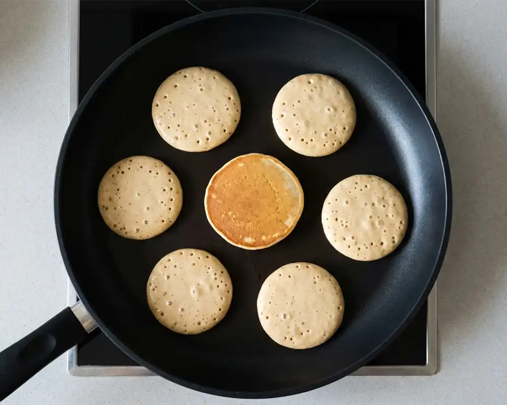Kleine Protein-Pancakes in beschichteter Pfanne beim Backen von oben