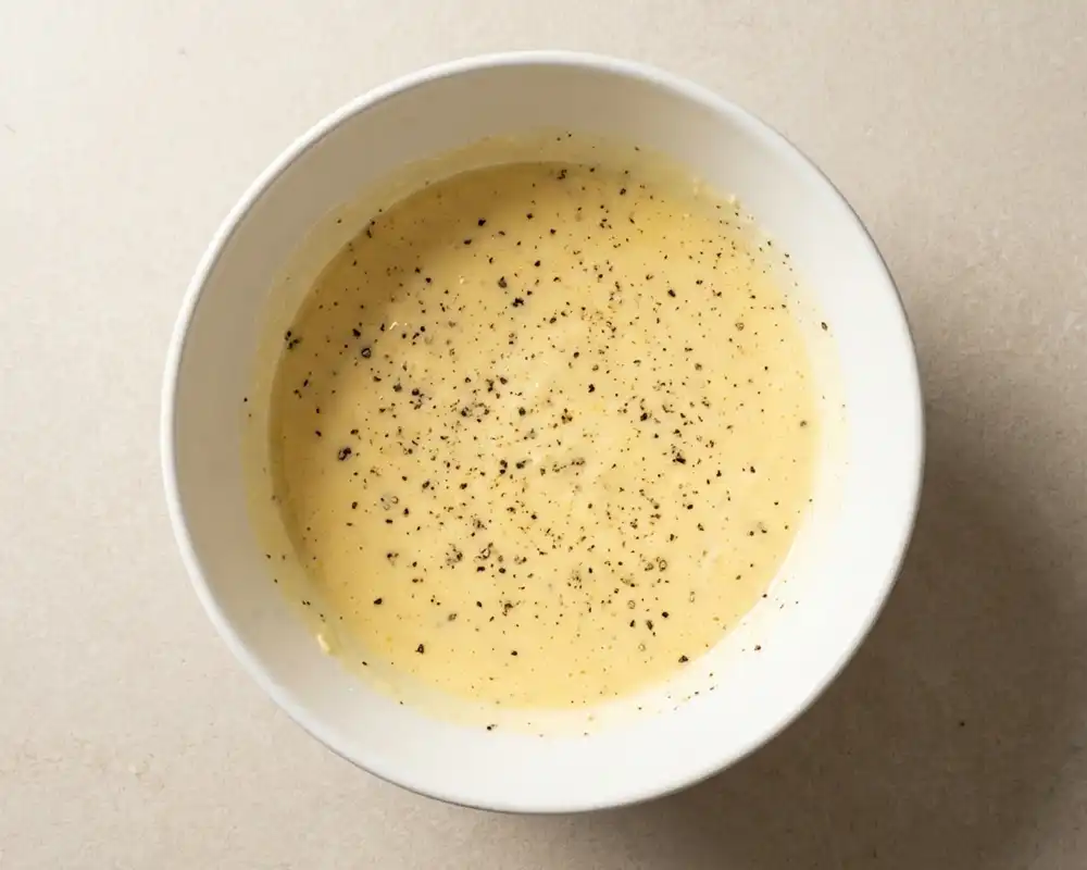 Ei-Quark-Parmesan-Mischung mit schwarzem Pfeffer in weißer Schüssel