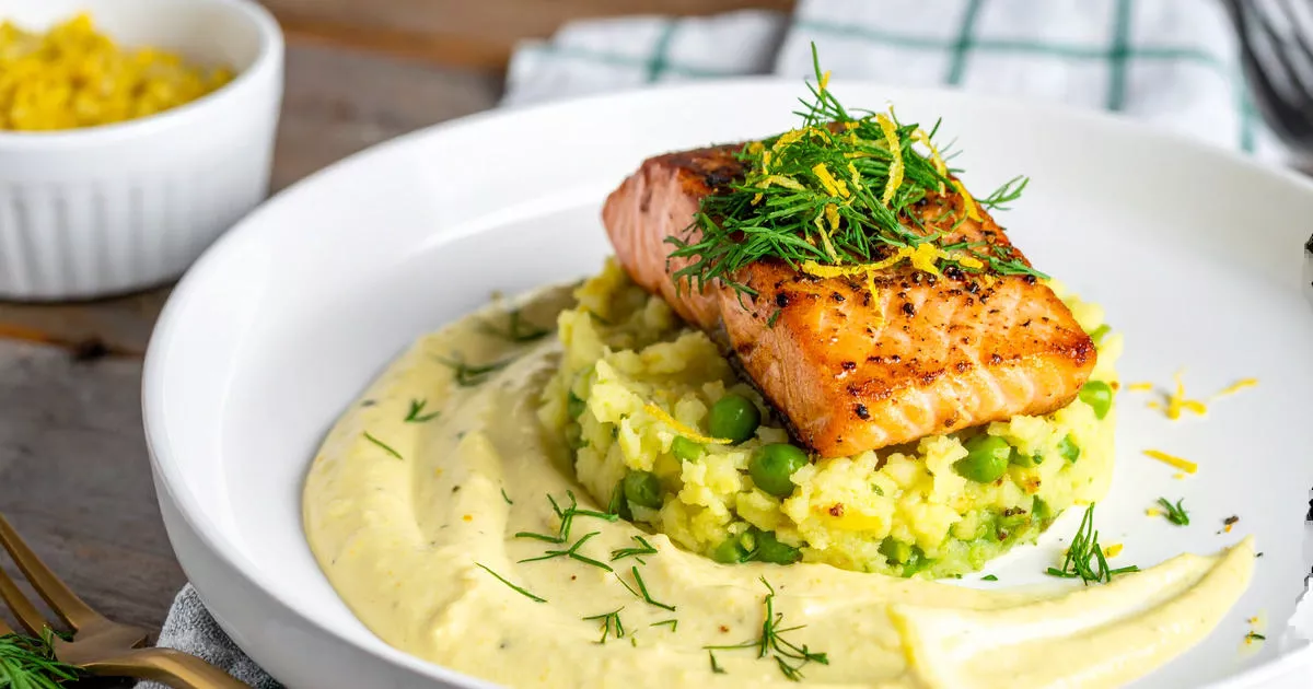 Kartoffel-Erbsen-Stampf mit gebratenem Lachsfilet und Senf-Dill-Skyr auf weißem Teller angerichtet