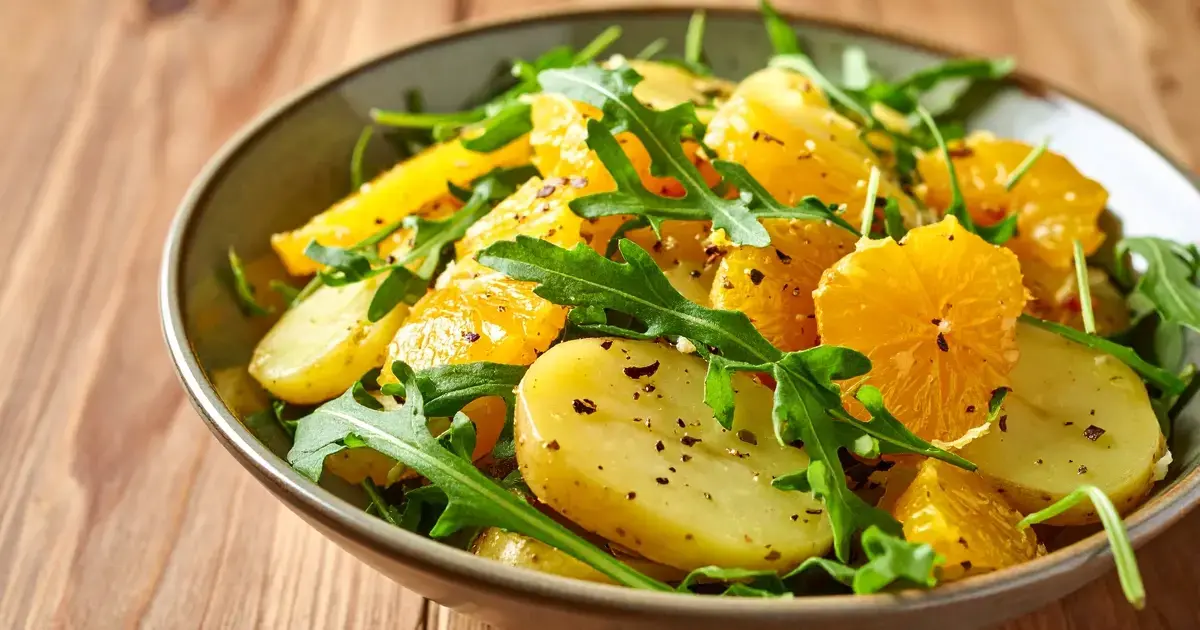 Kartoffelsalat mit Orange und Rucola in einer Schüssel angerichtet