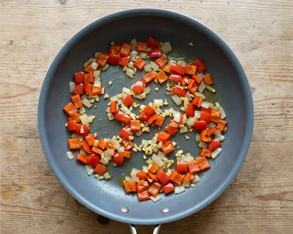 Angedünstete Paprika und Zwiebeln in Pfanne von oben fotografiert