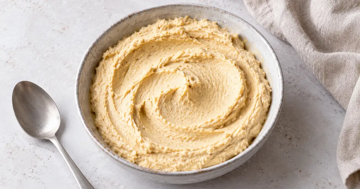 Cremiger Protein-Hummus mit Hüttenkäse und Kichererbsen in einer Keramikschale.
