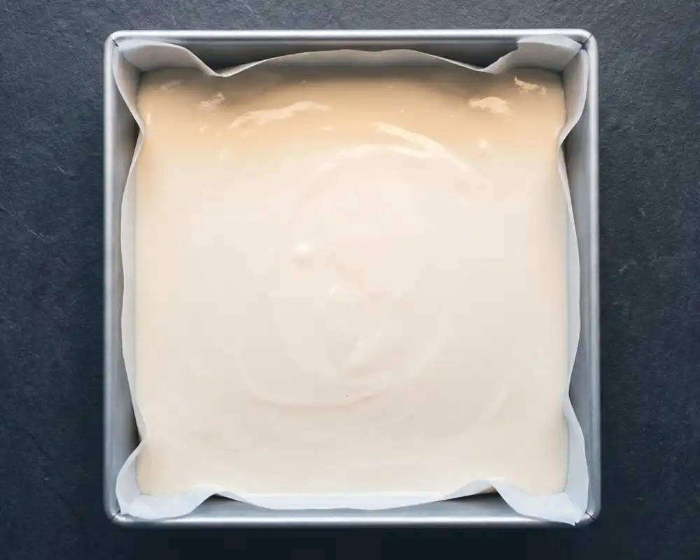 Glatt pürierter Frischkäse als Basis für gesunde Protein-Brownies in quadratischer Backform