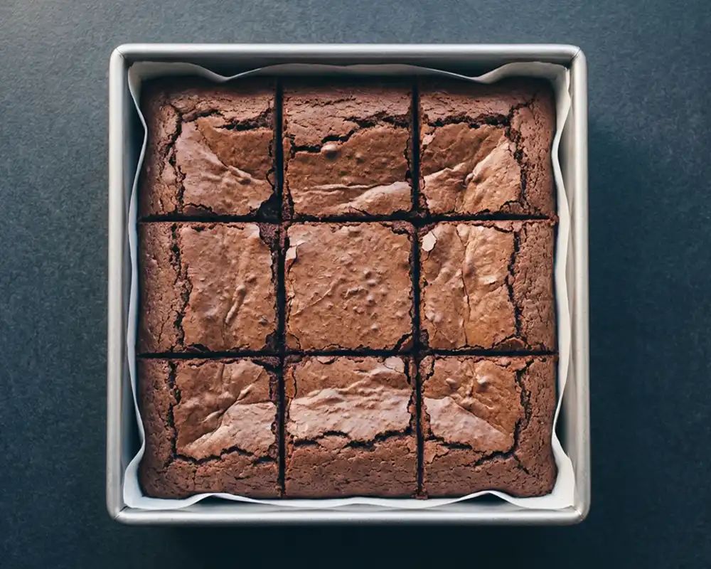 In neun Stücke geschnittene saftige Protein-Brownies in quadratischer Backform