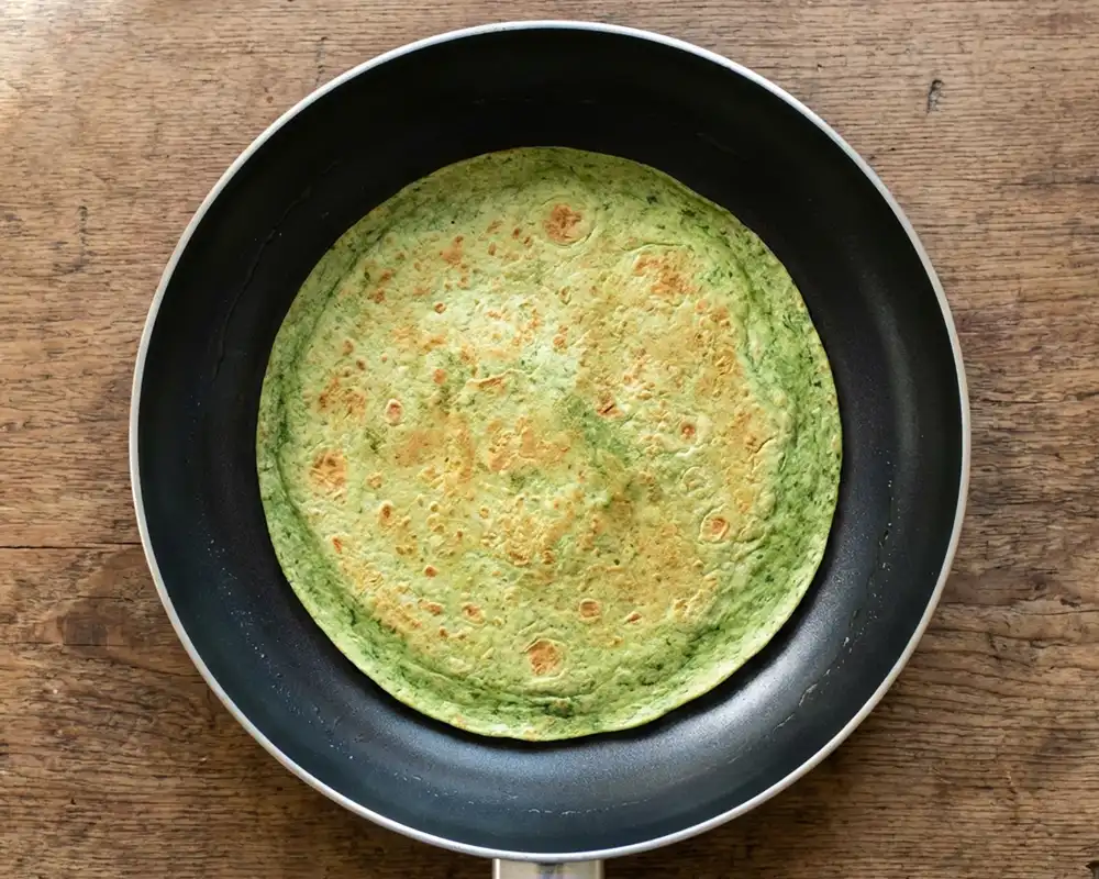 Fertig gebackener grüner Protein-Wrap in der Pfanne von oben