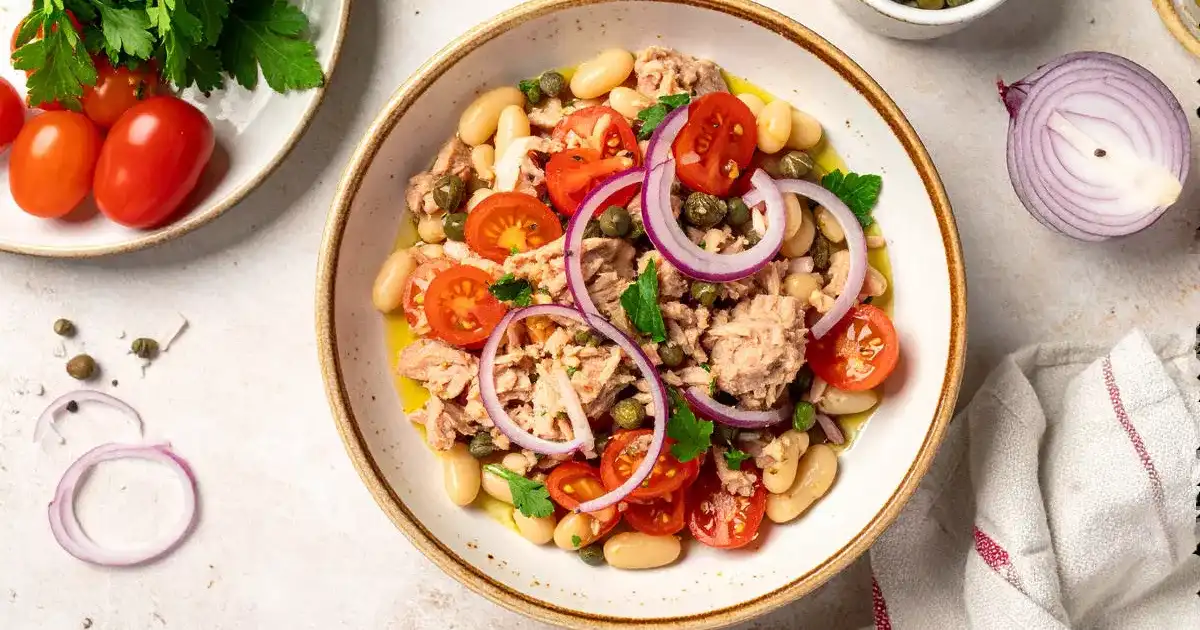 Mediterraner Bohnensalat mit Thunfisch, Zwiebeln, Tomaten und Petersilie in Schüssel serviert