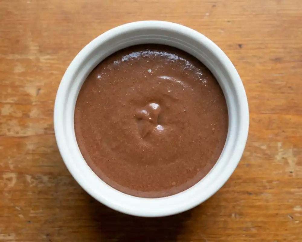 Glatter Schoko-Teig für Protein-Tassenkuchen in weißer Keramikform von oben fotografiert