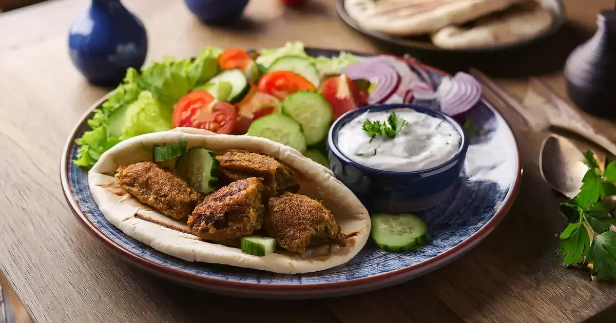 Veganes Seitan-Gyros mit Tzatziki, Salat und frischen Zutaten auf einem Teller.