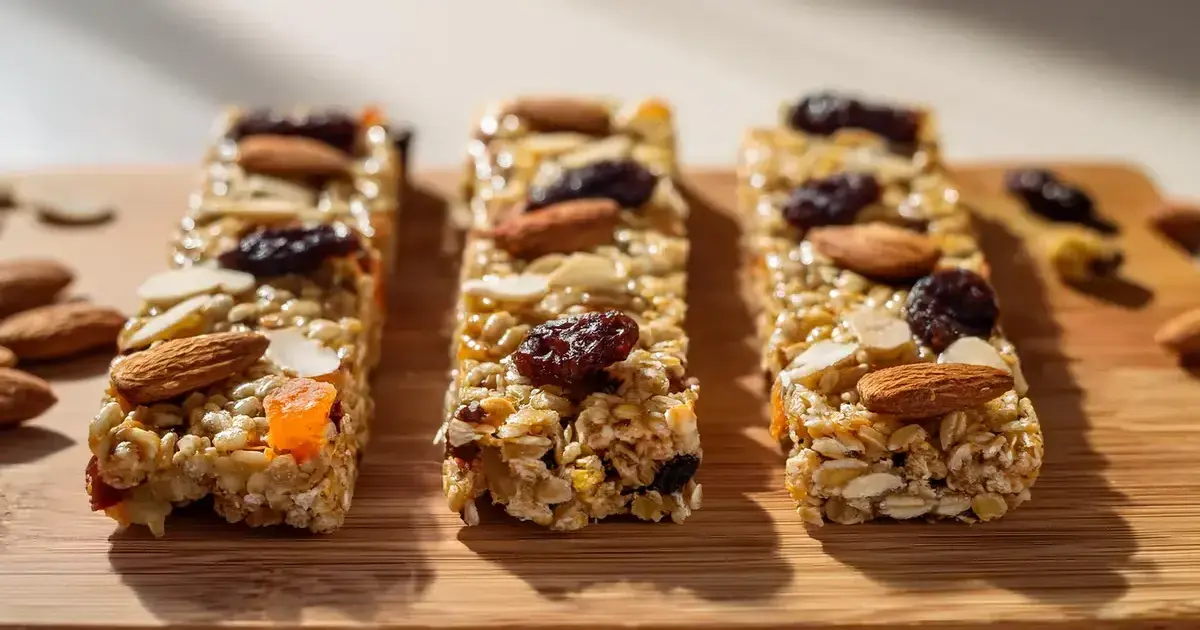 Selbstgemachte Energieriegel mit Haferflocken, Nüssen, Trockenfrüchten und gepufftem Quinoa auf einem Holzbrett