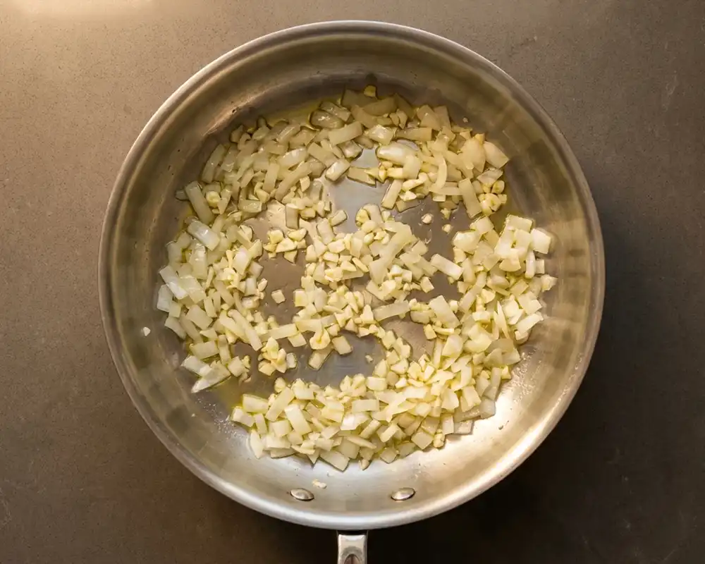 Fein gehackte Zwiebeln und Knoblauch glasig in der Pfanne