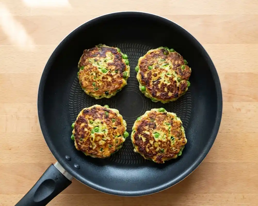 Zucchini-Erbsen-Puffer goldbraun in Pfanne gebraten